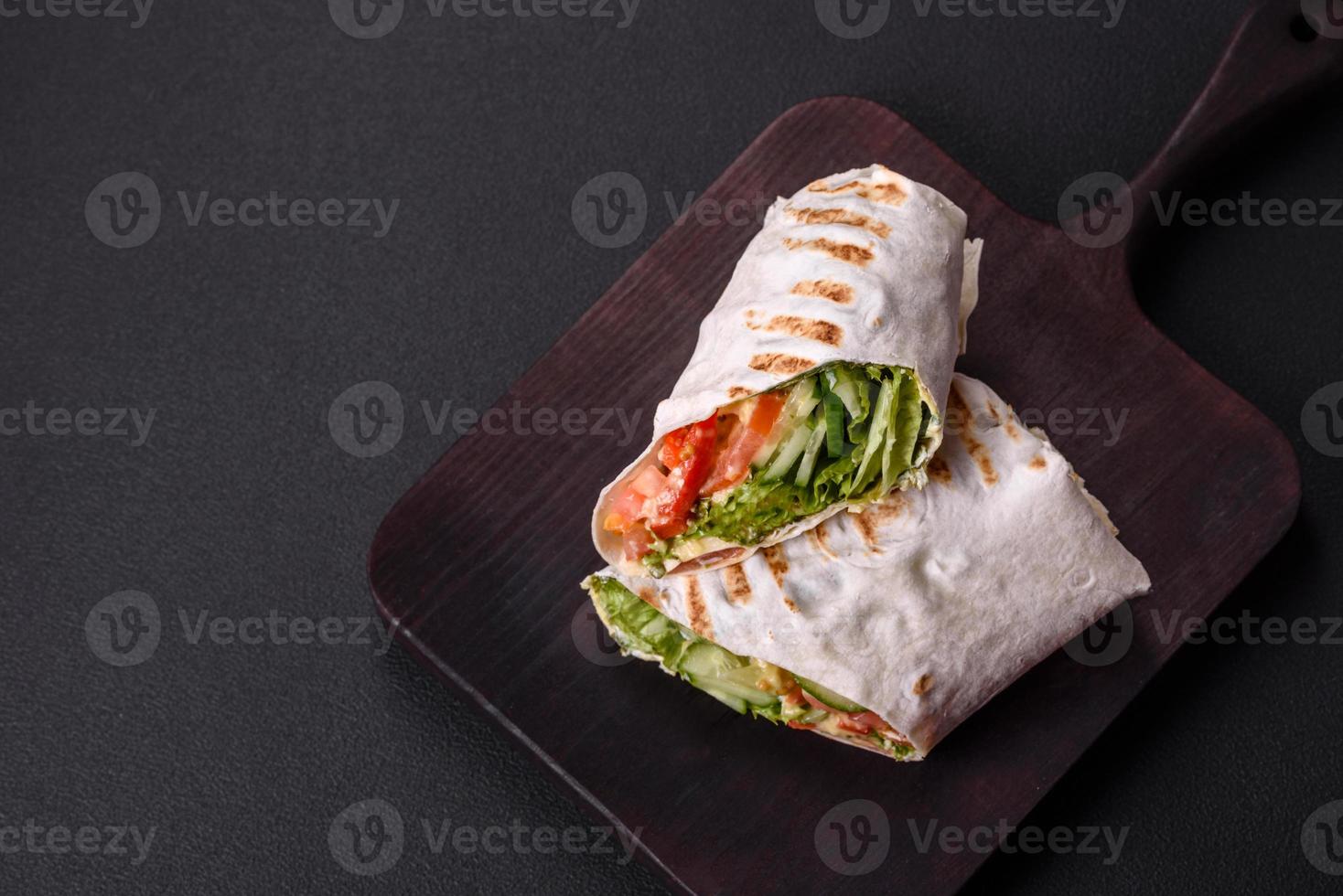 delicioso shawarma fresco con tomates, pimientos, pepino sobre un fondo de hormigón oscuro foto