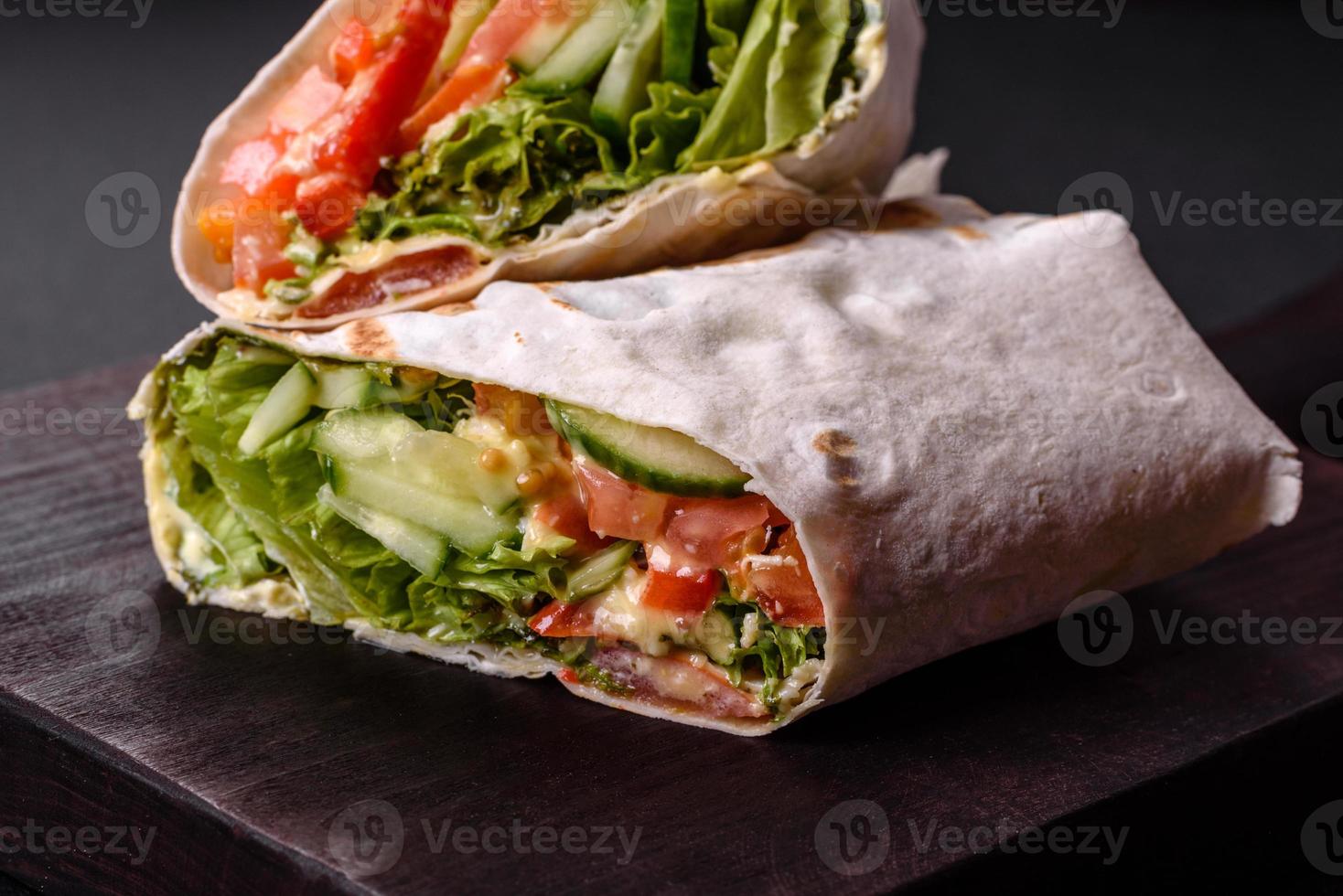 delicioso shawarma fresco con tomates, pimientos, pepino sobre un fondo de hormigón oscuro foto