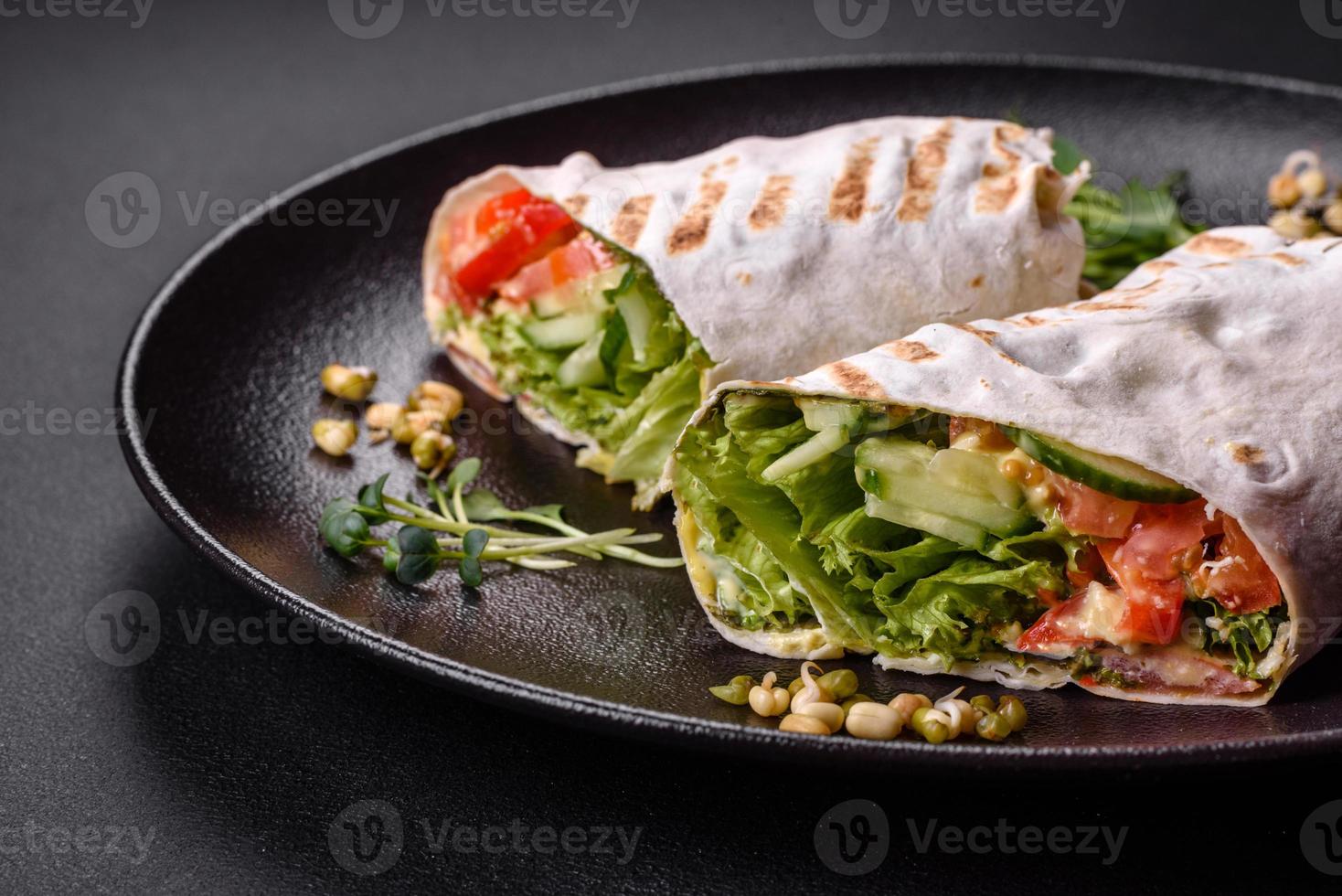 Delicious fresh shawarma with tomatoes, peppers, cucumber on a dark