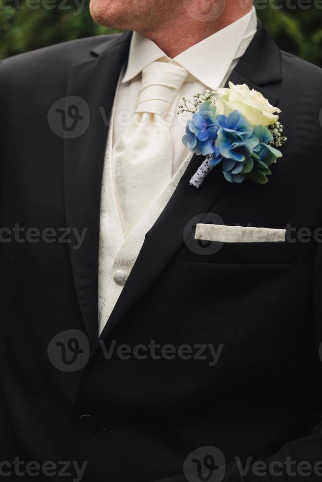 el novio con traje de novio negro, esmoquin con camisa blanca, corbata y ojal de rosas. foto de alta calidad
