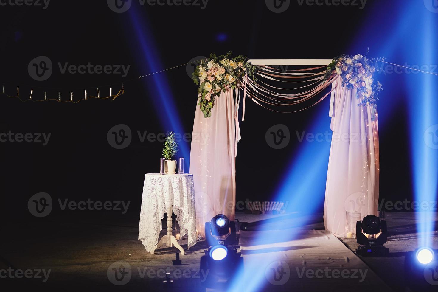 Ceremonia nocturna con espectáculo de luces y fuego. el arco de la boda está decorado con flores en la ceremonia nocturna al aire libre en el jardín con luces. foto