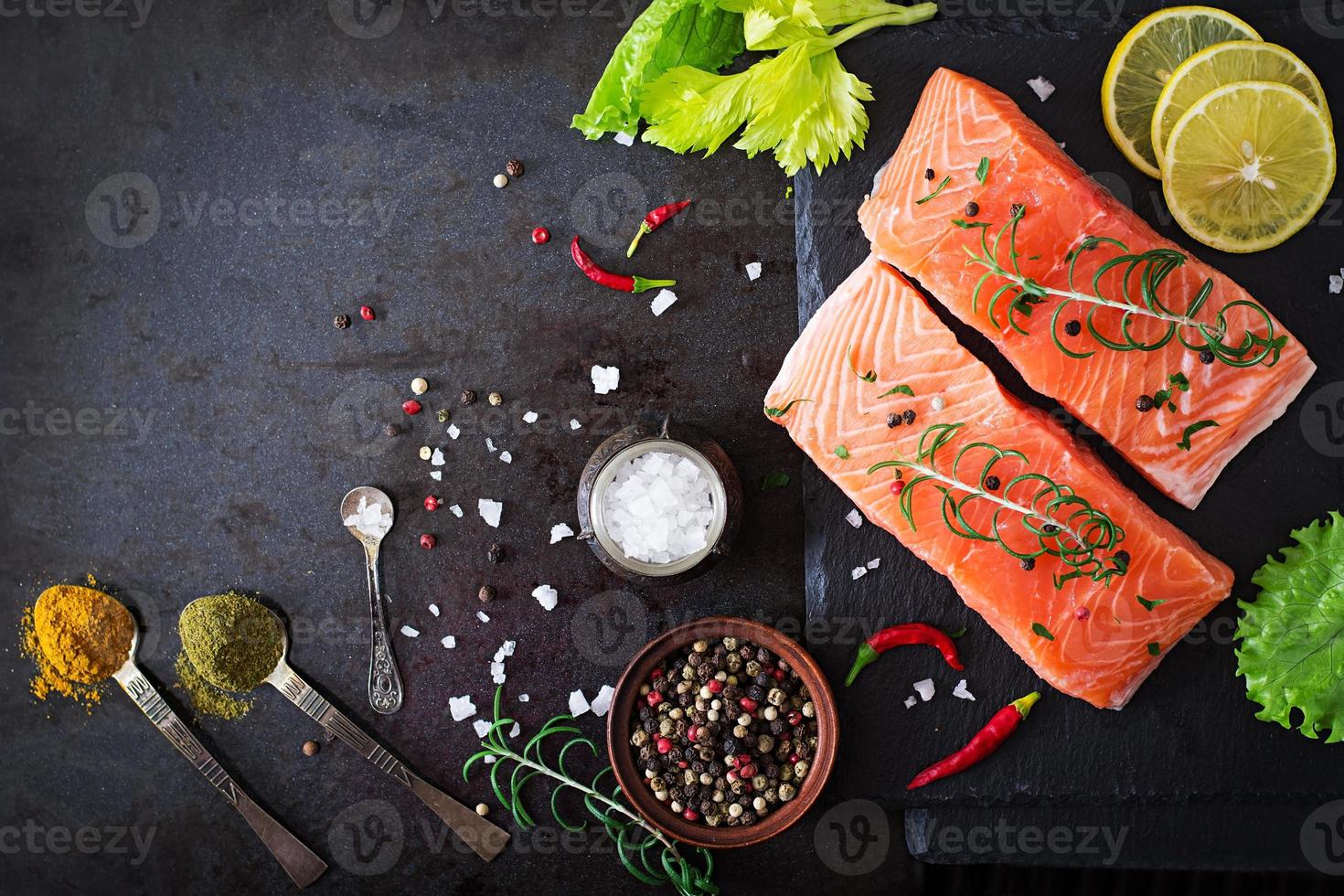 Raw salmon fillet and ingredients for cooking on a dark background in a rustic style. photo