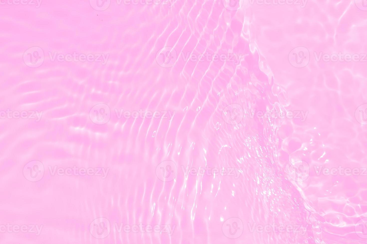 Defocus blurred transparent pink colored clear calm water surface texture with splashes and bubbles. Trendy abstract nature background. Water waves in sunlight with caustics. Pink water shinning photo