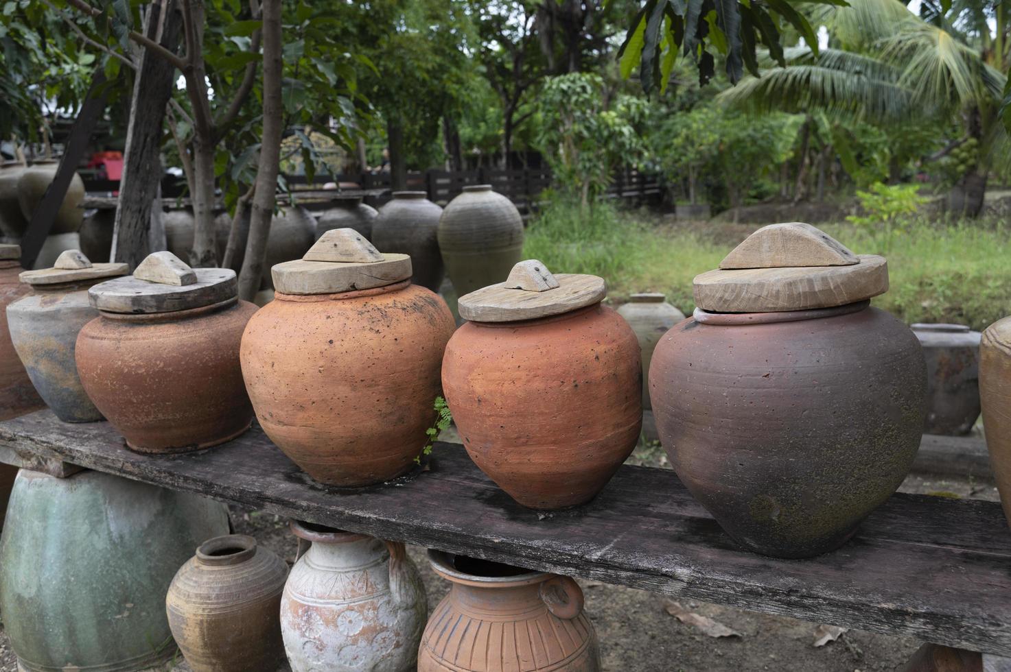 Several ancient terracotta jars with wooden lids on top. photo