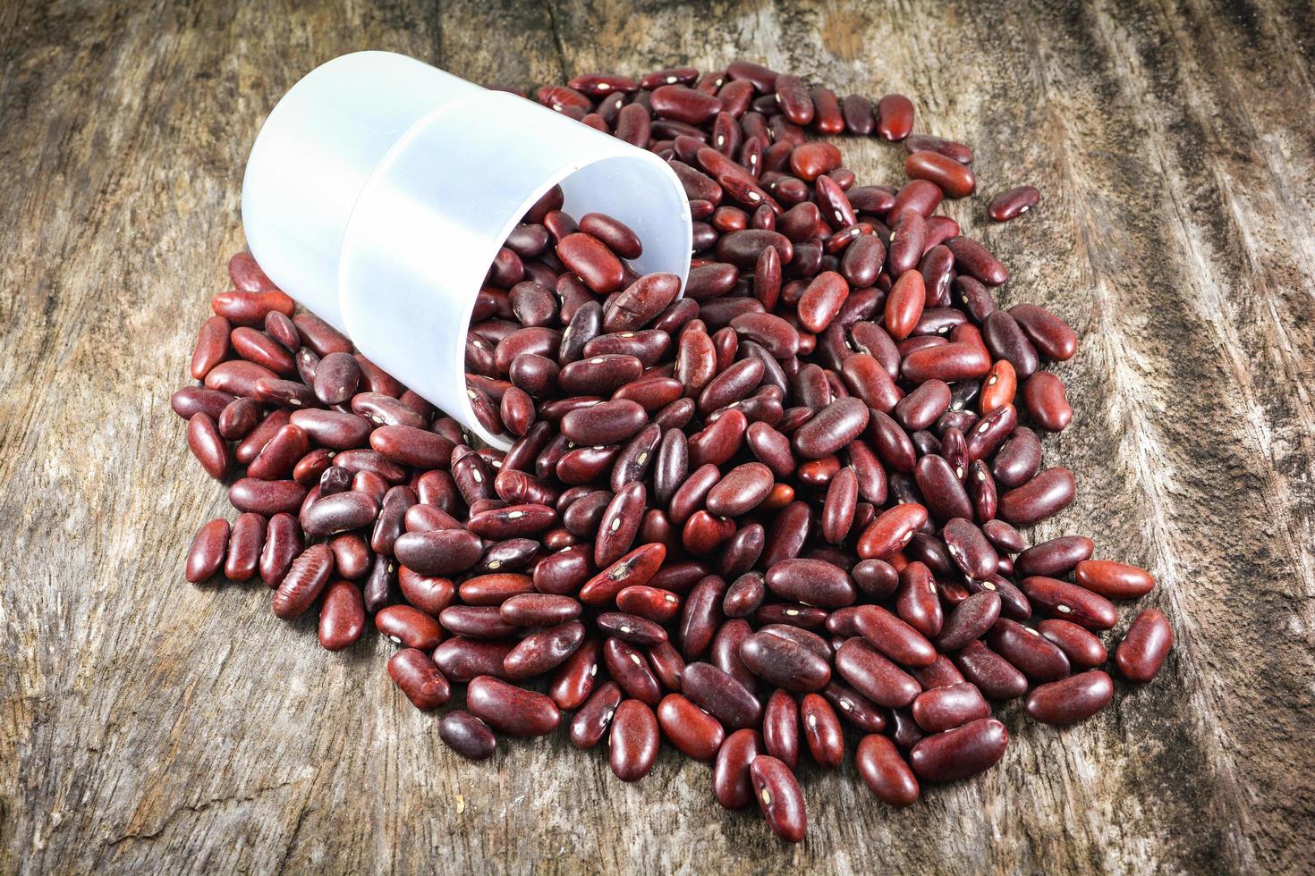 Red beans azuki or red kidney bean grain seed with cup on rustic wood background photo