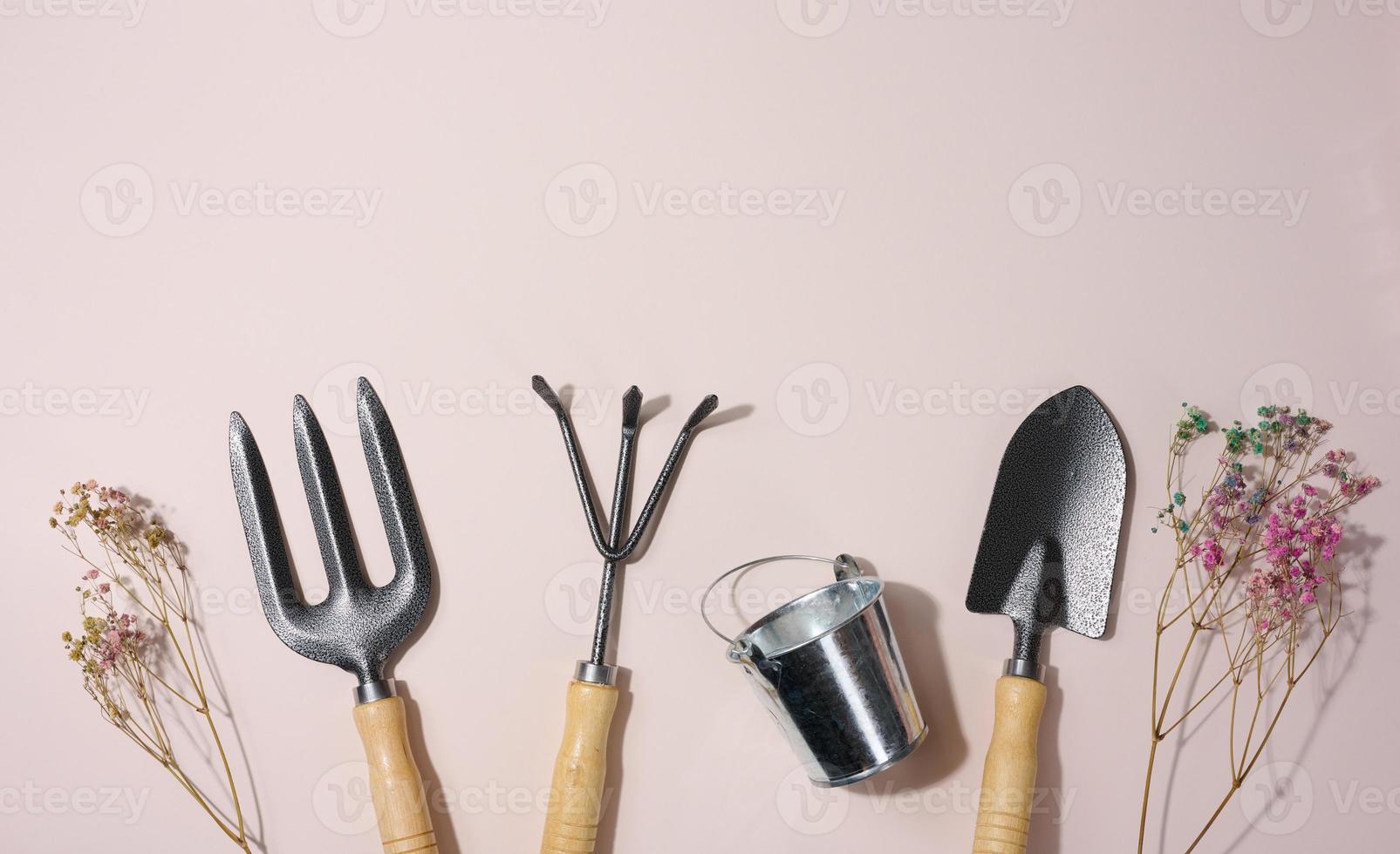 Garden shovel and metal bucket on beige background, top view photo