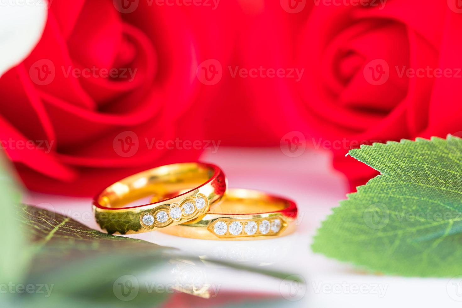 Cerrar anillo de oro y rosas rojas sobre blanco foto