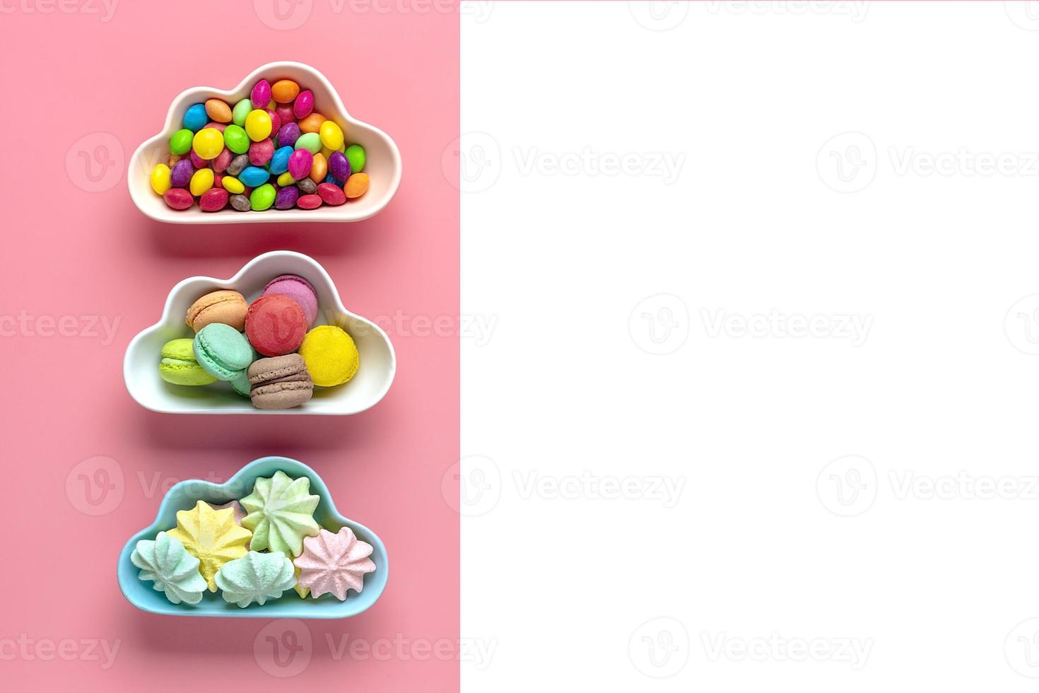 Caramelos coloridos: piruletas, merengues, macarrones en un tazón en forma de nube aislado en rosa, fondo blanco vista plana superior knolling comida poco saludable y sabrosa concepto creativo tarjeta de vacaciones foto