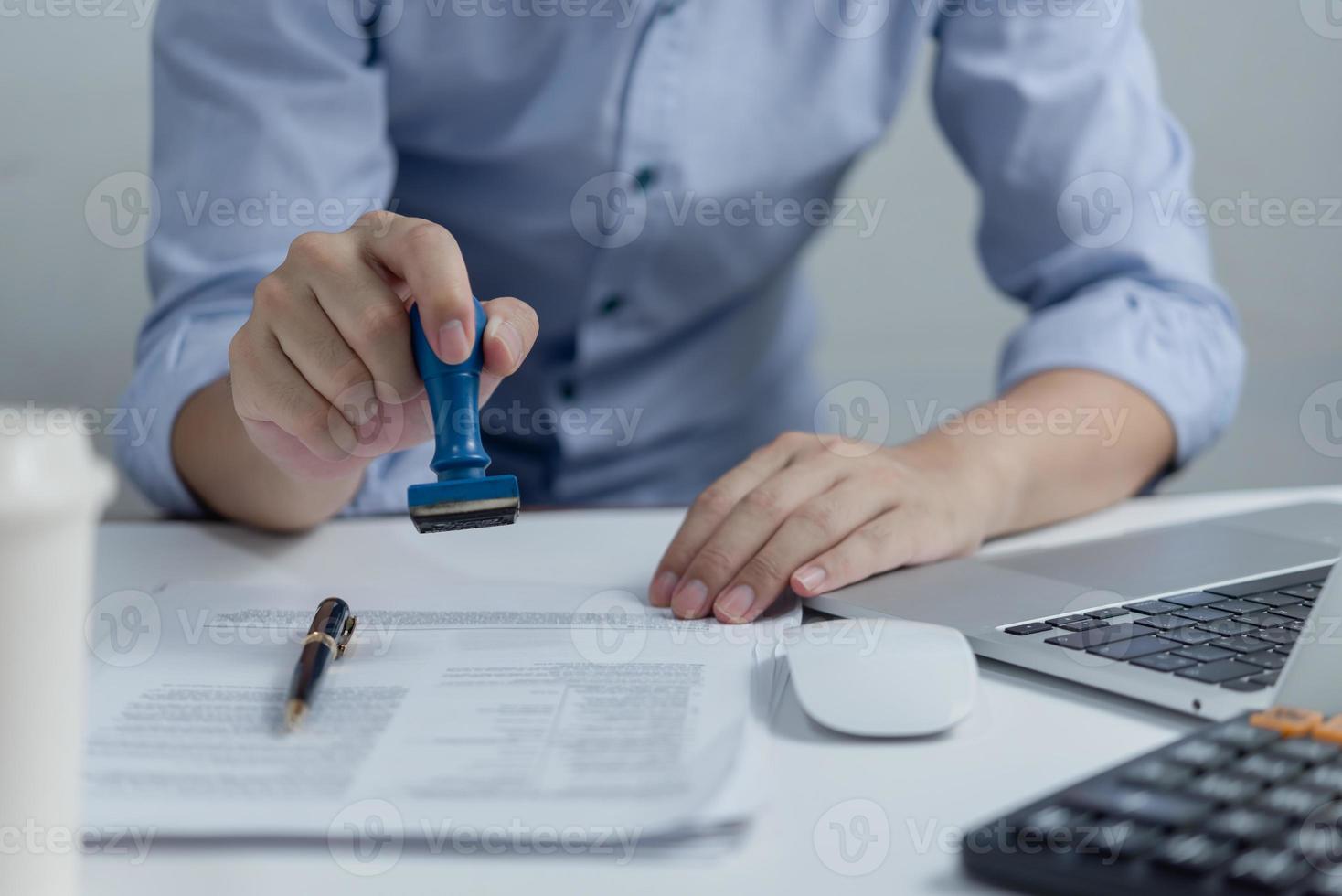 Man stamping approval of work finance banking or investment marketing documents on desk. photo