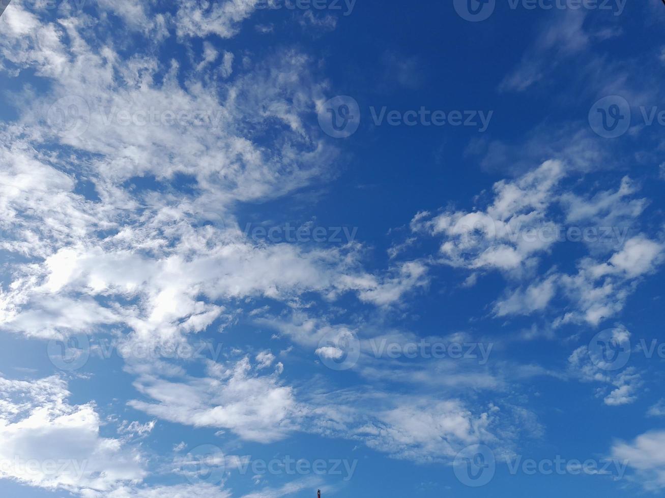 White clouds in the blue sky. Heaven and infinity. Beautiful bright blue background. Light cloudy, good weather. Curly clouds on a sunny day. photo