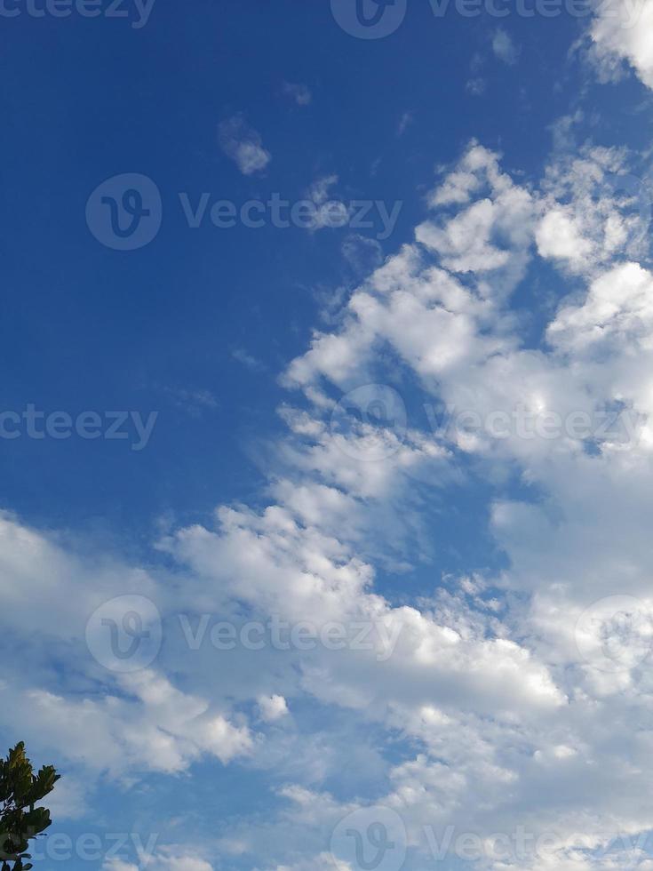 White clouds in the blue sky. Heaven and infinity. Beautiful bright blue background. Light cloudy, good weather. Curly clouds on a sunny day. photo