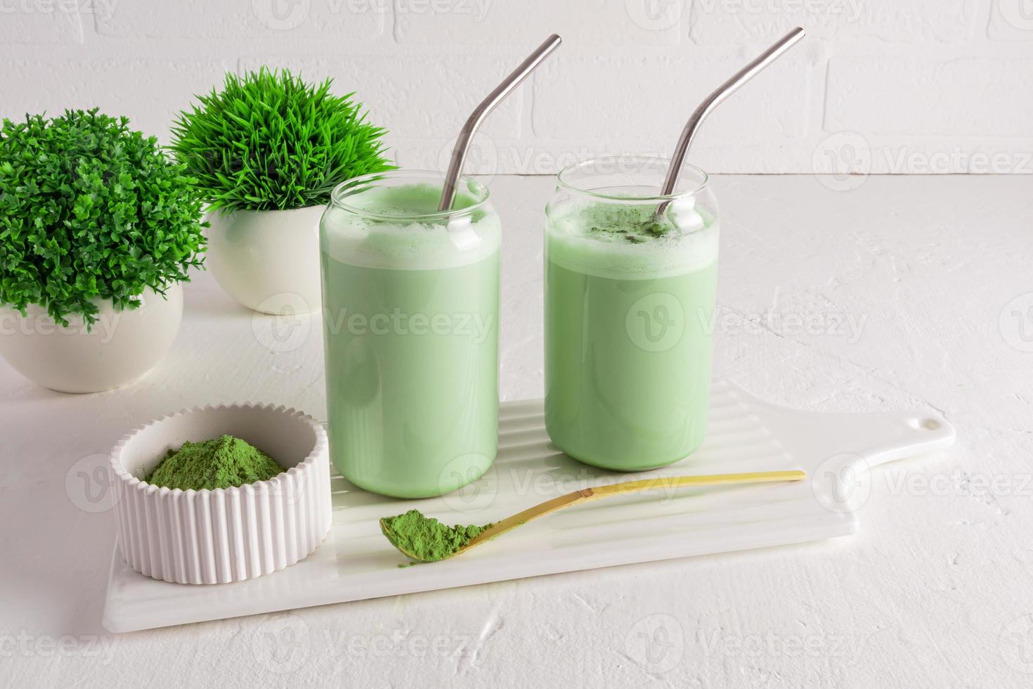 dos vasos modernos en forma de lata de cerveza con té matcha helado con paja en un tablero contra una pared de ladrillo. una alternativa al café. cafeína. foto