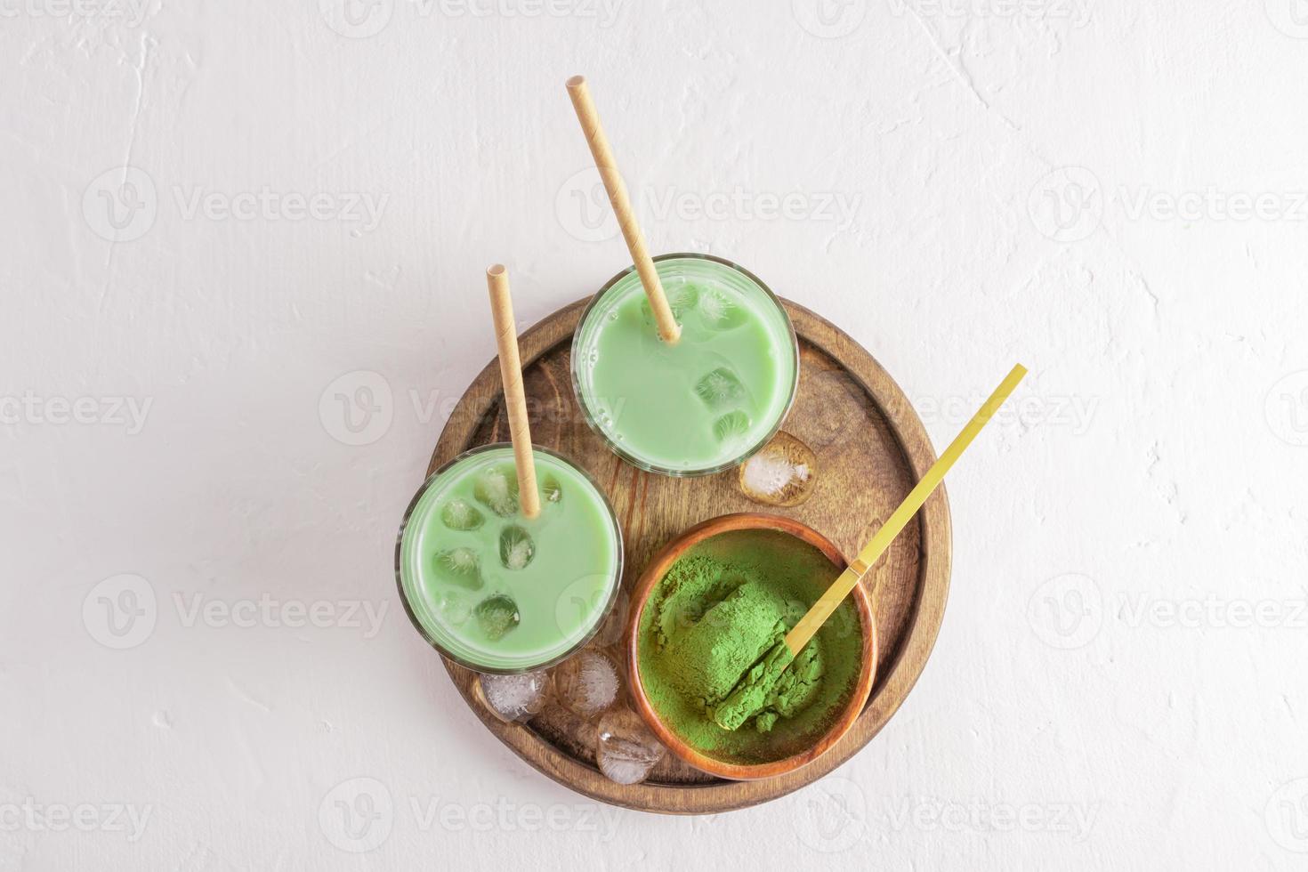 iced tea latte with ice cubes in two glasses with eco-straw on a wooden round tray. top view. space for text. white background. Detox. photo
