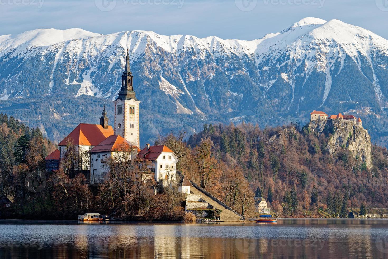 amanecer paisaje invernal del lago mágico bled en eslovenia. un cuento de invierno para experiencias románticas. montañas con nieve en el fondo. iglesia de la madre de dios en una pequeña isla en el lago. foto