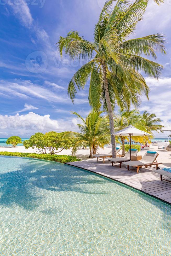 hermoso paraguas de lujo y silla alrededor de la piscina al aire libre en el hotel y resort con palmera de coco en el cielo azul. lujosas vacaciones de verano y banner de vacaciones. impulsar el procesamiento de color foto