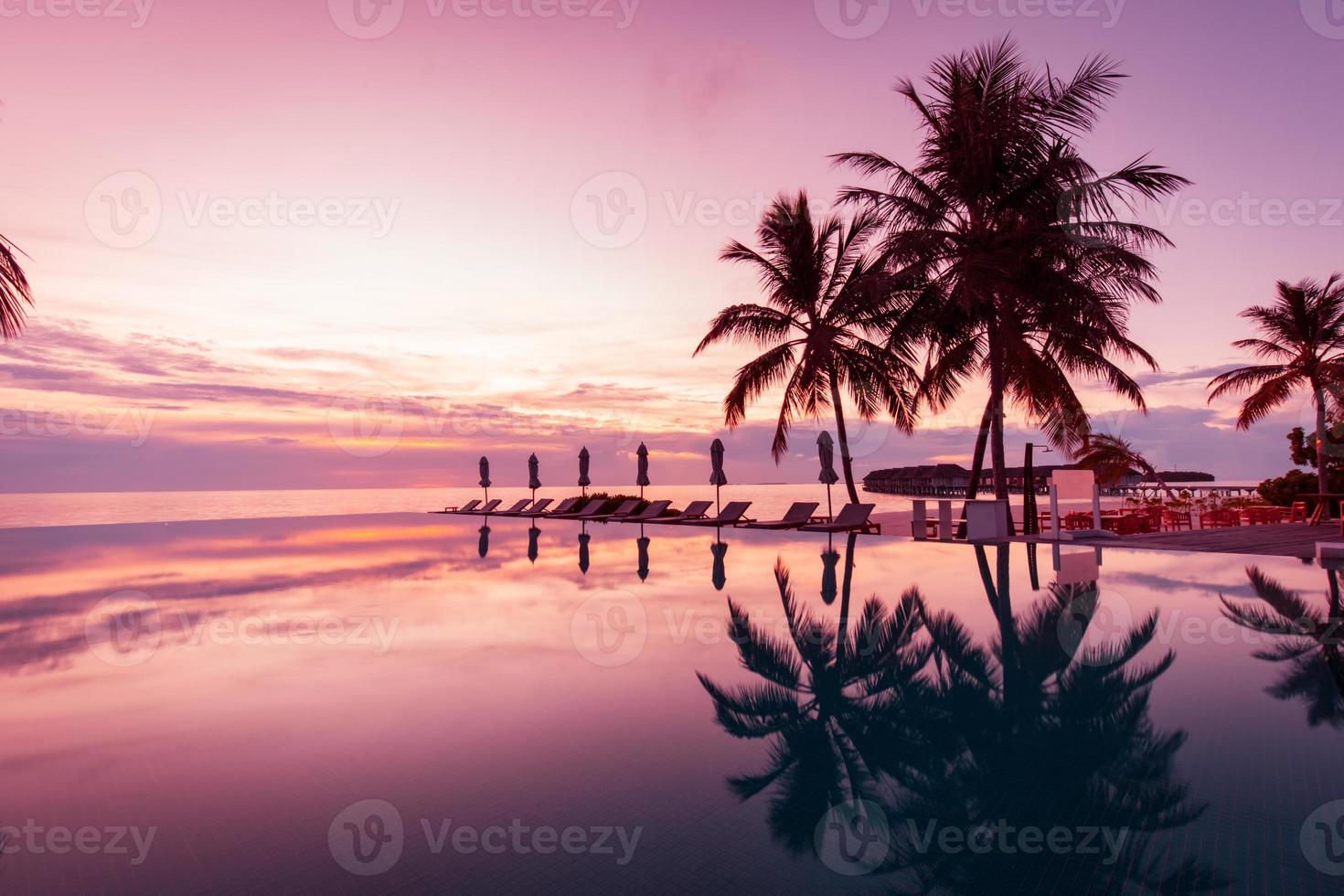 Luxury swimming pool on the beach, tranquil scene of exotic tropical landscape with copy space, summer background for vacation holidays. Beautiful poolside and sunset sky. Luxurious tropical beach photo