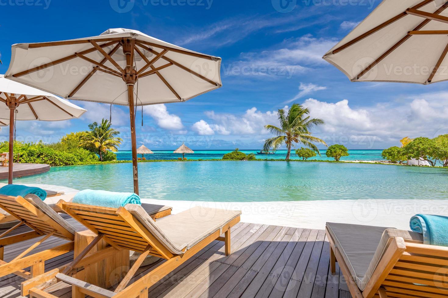 hermoso paraguas de lujo y silla alrededor de la piscina al aire libre en el hotel y resort con palmera de coco en el cielo azul. lujosas vacaciones de verano y banner de vacaciones. impulsar el procesamiento de color foto