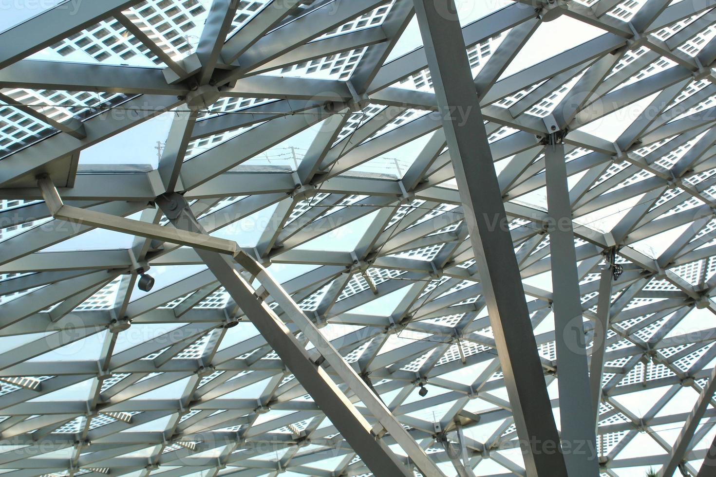 Transparent glass dome roof of modern design style pavilion building with geometric metal construction pattern. View of blue sky and clouds. Abstract structure triangle high-tech architecture window. photo