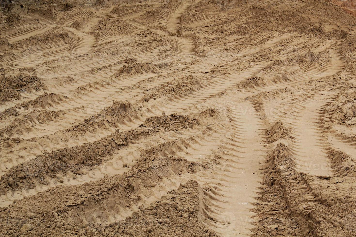 Tire track mark lines shape on dry sand background. Trail tyre imprint from heavy machinery. Vehicle shape. Road construction site backdrop concept. Trace of wheel pattern on mud. Nature texture. photo