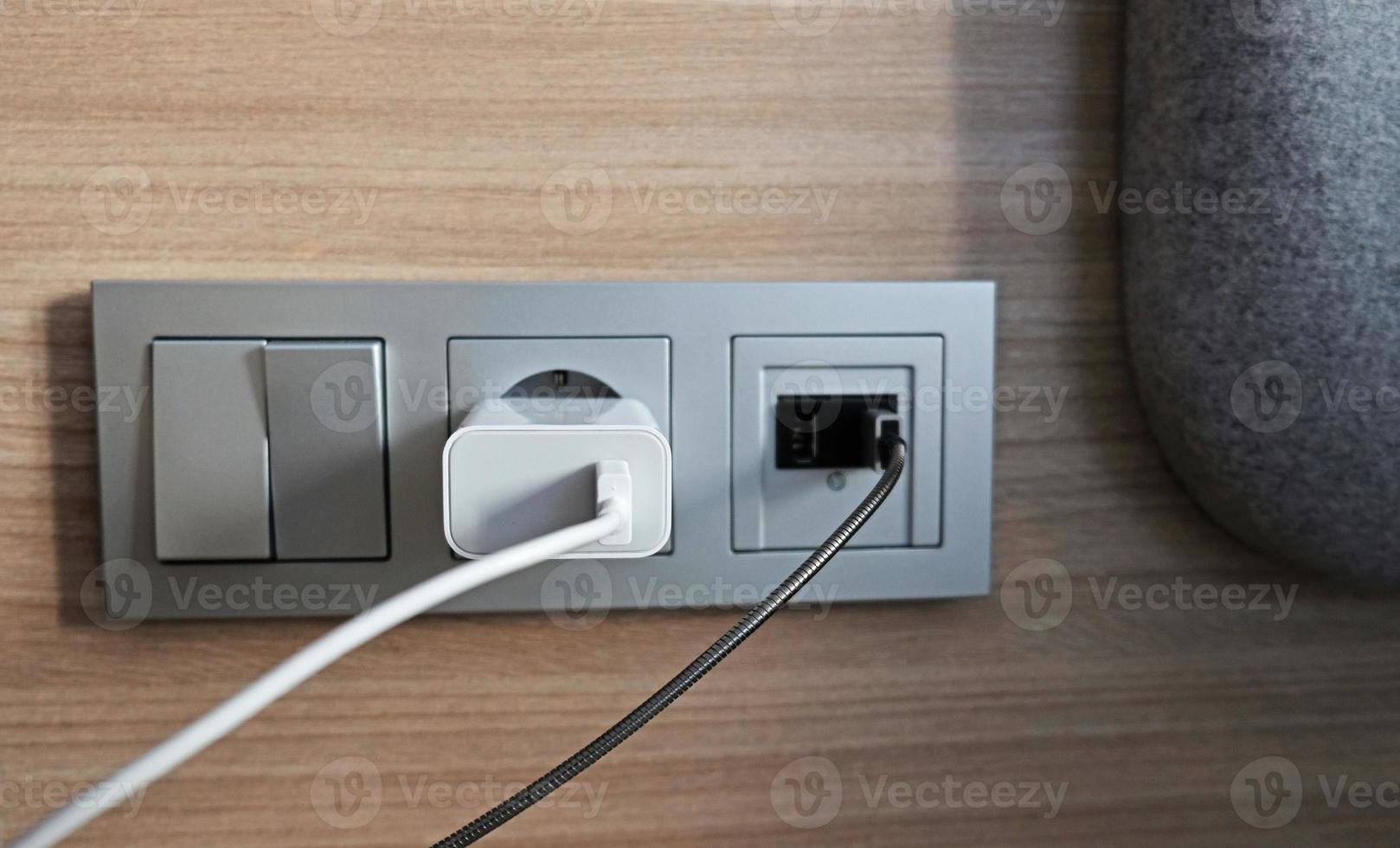 toma de corriente eléctrica, toma usb, interruptor de luz en el panel de madera en el interior del hotel. para mayor comodidad, el cargador móvil o smartphone en el concepto de la vida moderna. de cerca. foto