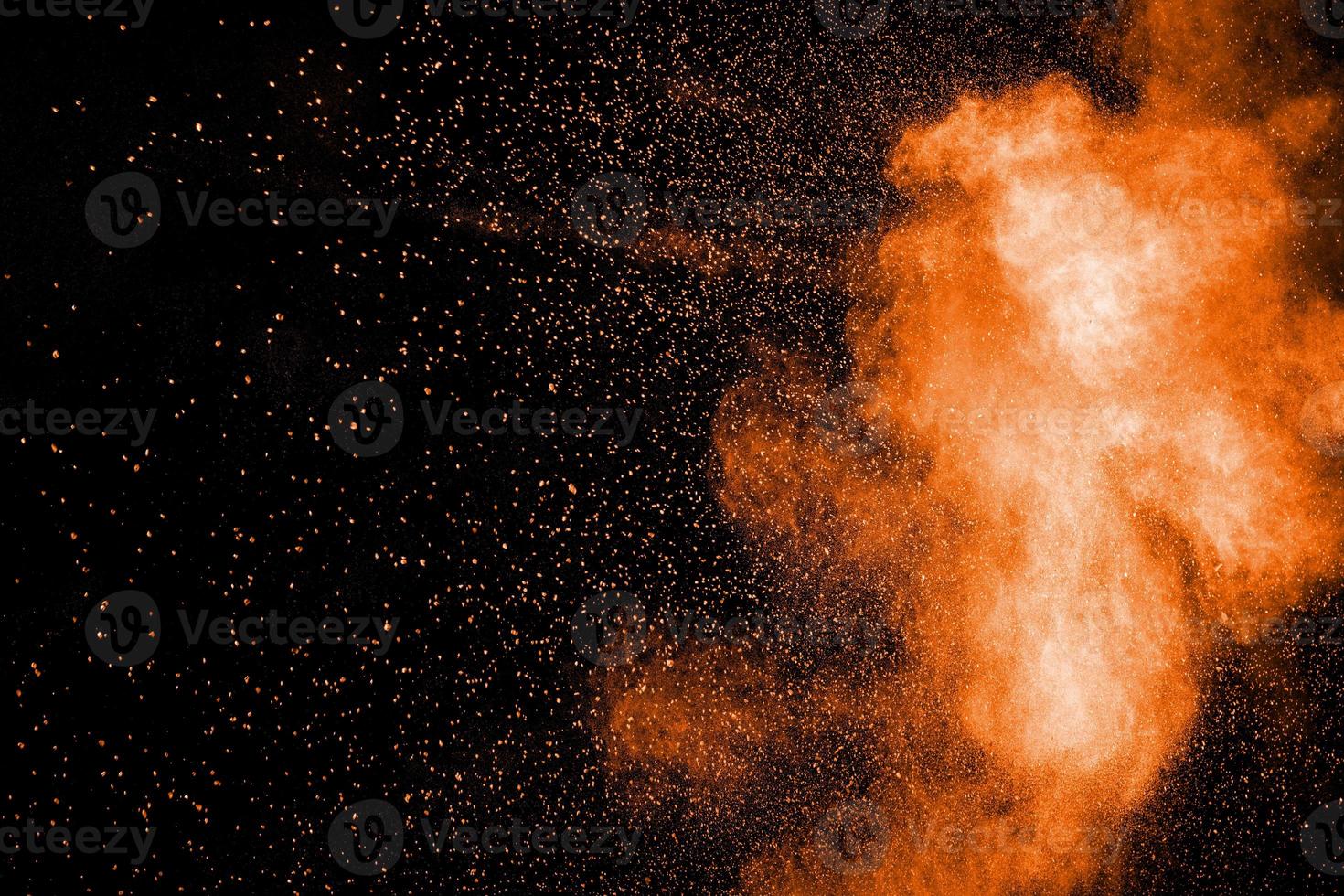 Orange color powder explosion cloud  on black background. photo