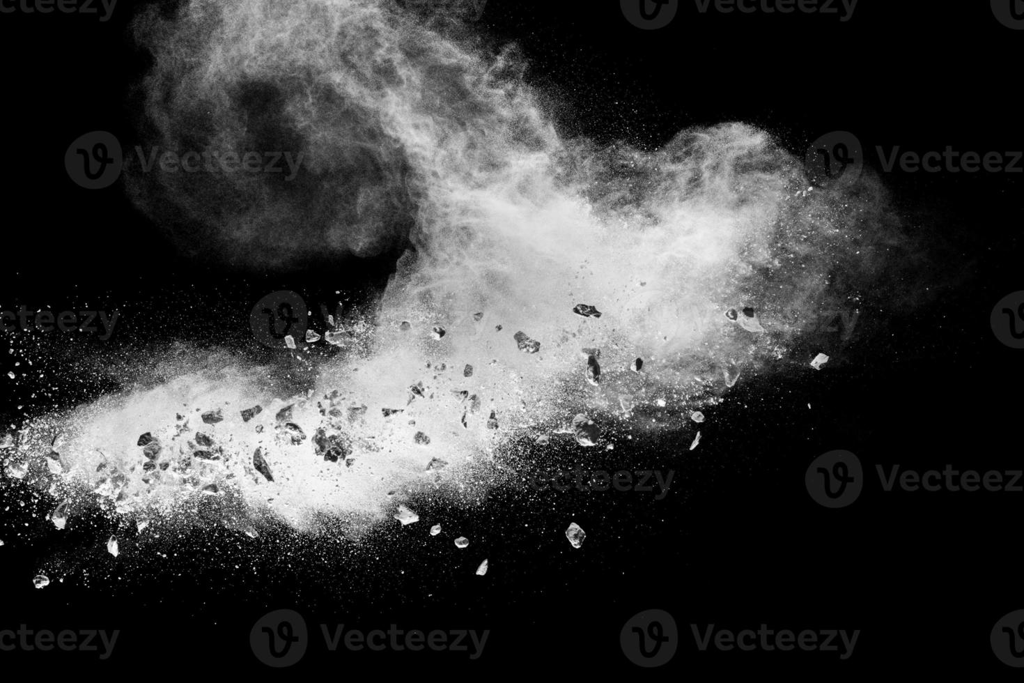 White powder with small stones on black background. Small granite rock stone fly on dust against dark background. photo