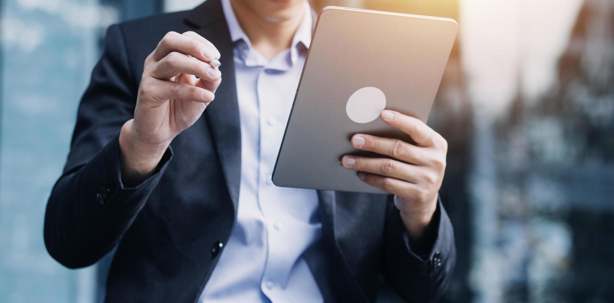 hombre de negocios asiático y mujer hermosa joven que trabajan en una tableta digital de pie fuera del edificio de oficinas. foto