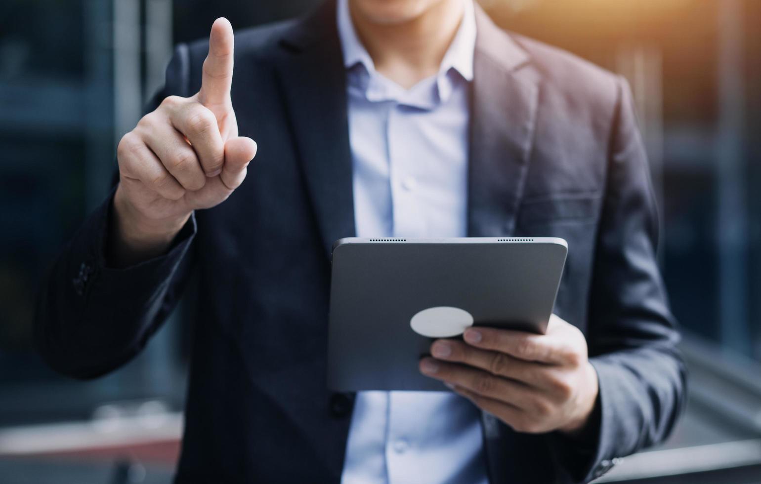 hombre de negocios asiático y mujer hermosa joven que trabajan en una tableta digital de pie fuera del edificio de oficinas. foto