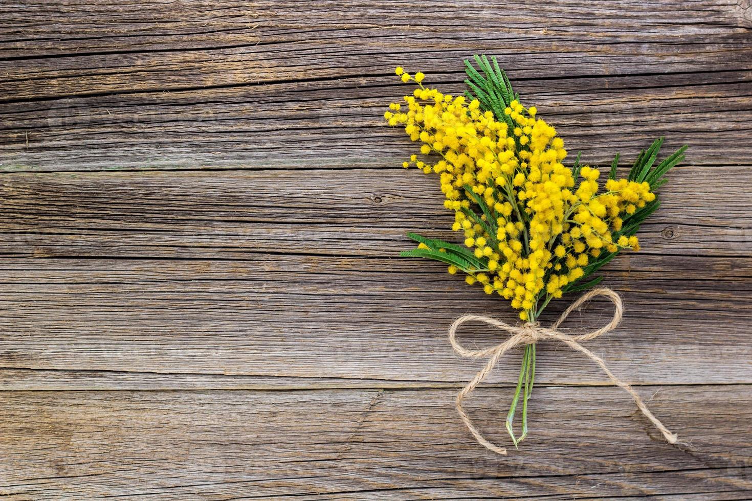 Yellow spring Mimosa bouquet with bow on a rustic wooden background with copyspace. photo