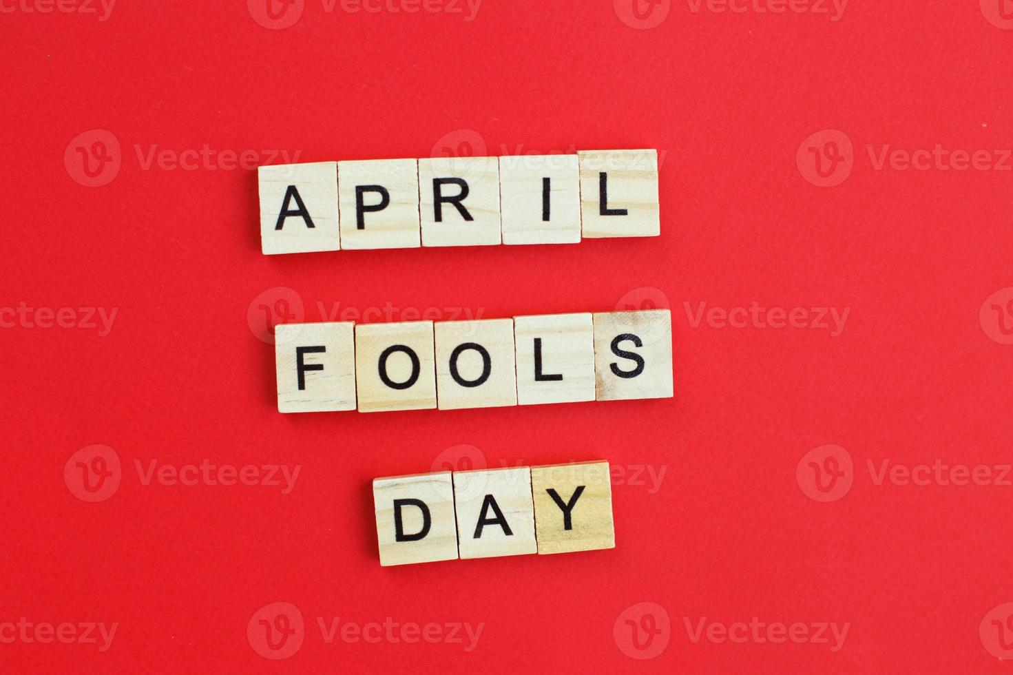 inscription april fools day made by wooden cubes on red background. photo