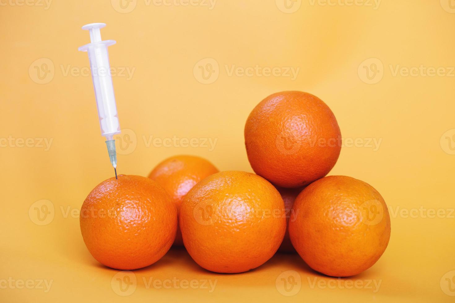 orange fruits with syringe extracting liquid with vitamin C. natural anti aging cosmetics concept photo