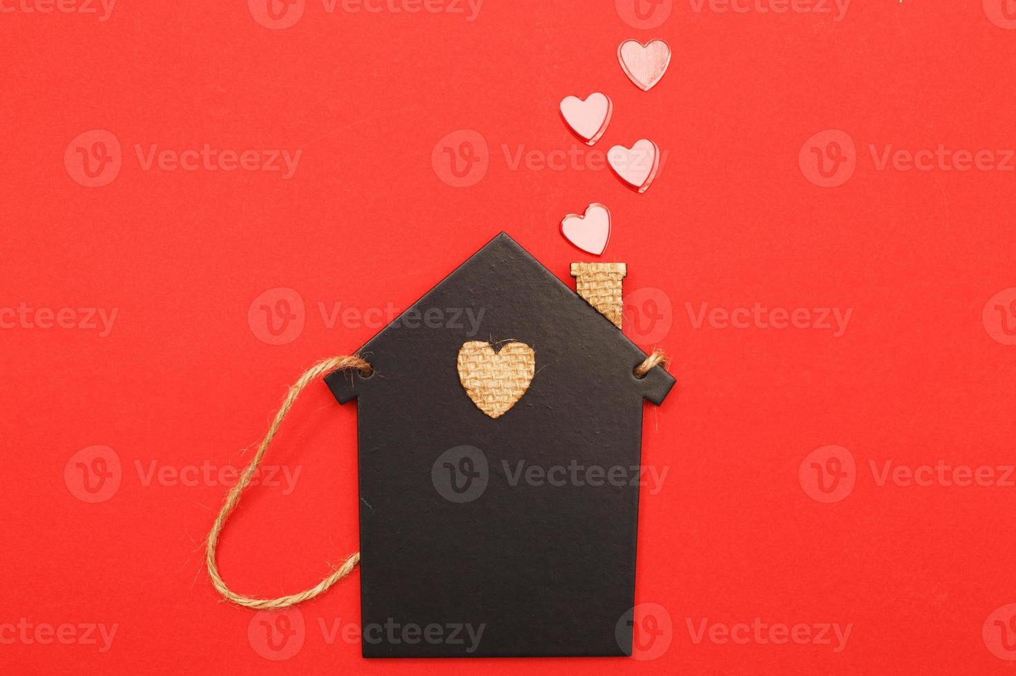 small toy house with red hearts from pipe on red background. Concept of love , family photo