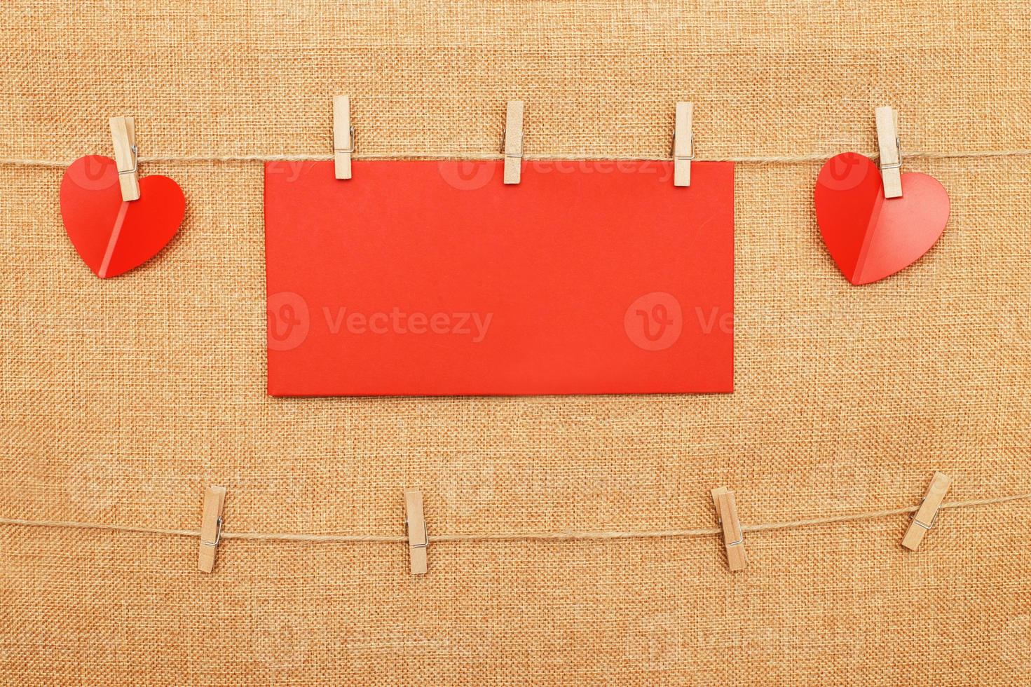 red hearts with paper note for text on clothes pin on brown textile background photo