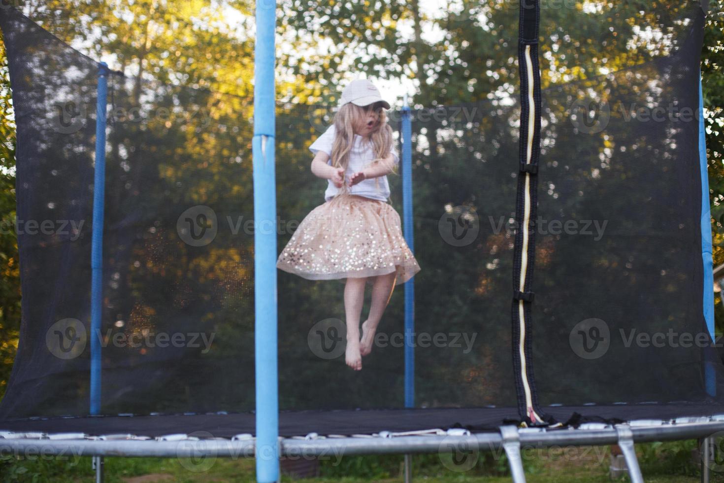 Little child girl jumping on the trampoline in the back yard photo