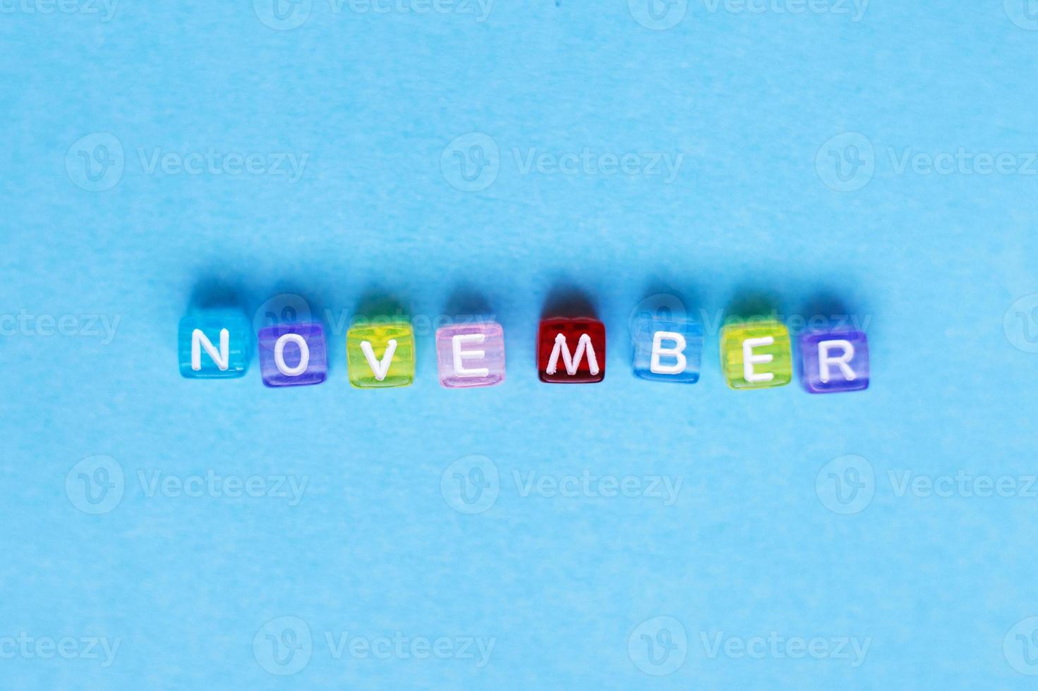 inscription november made by multicolor plastic cubes on a blue background. photo