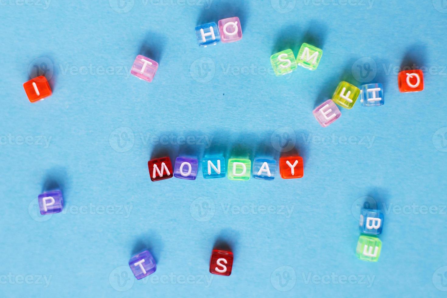 inscription Monday made by multicolor plastic cubes on a blue background. photo