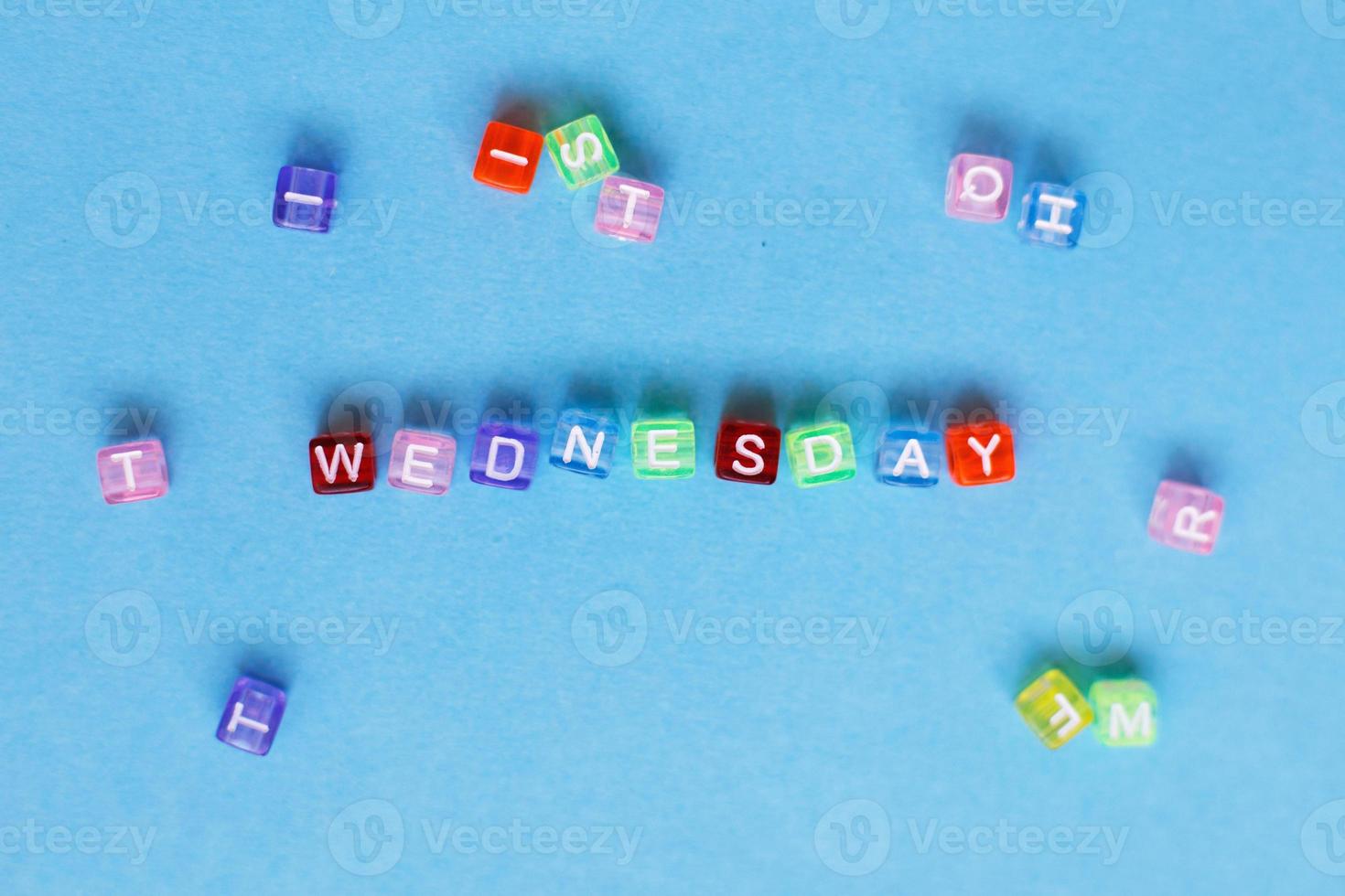 inscription wednesday made by multicolor plastic cubes on a blue background. photo