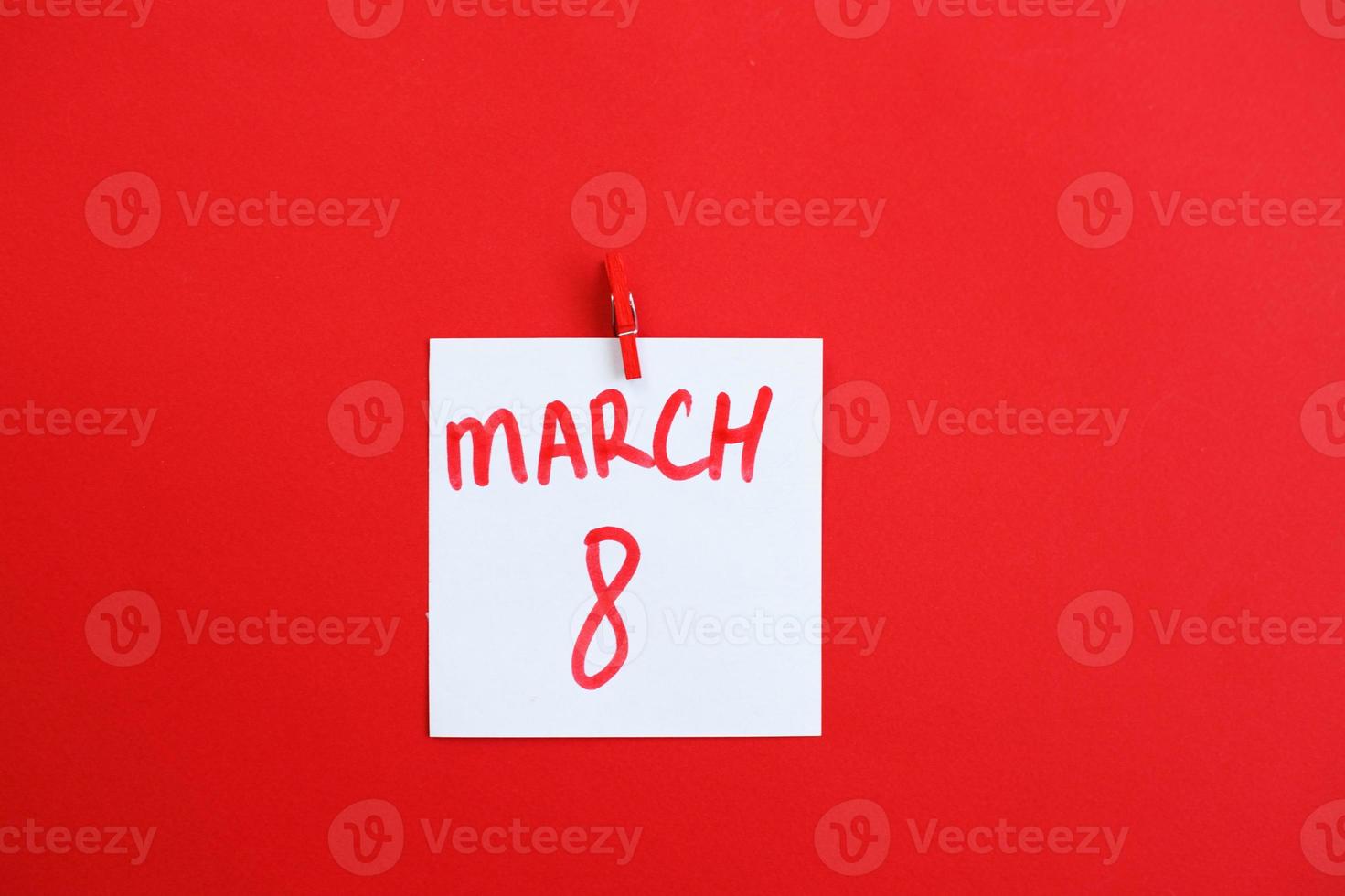 sticker with text March 8 hanging on the pin on the red background. Copy space for text. photo
