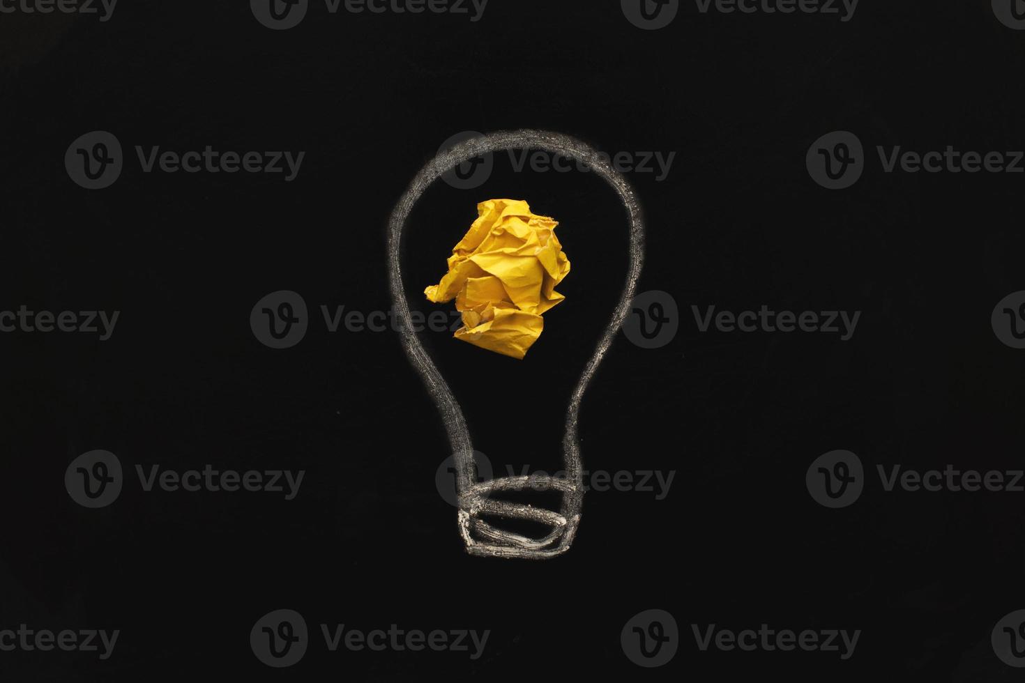 crumpled yelllow paper laightbulb as a concept creative idea on a blackboard background photo