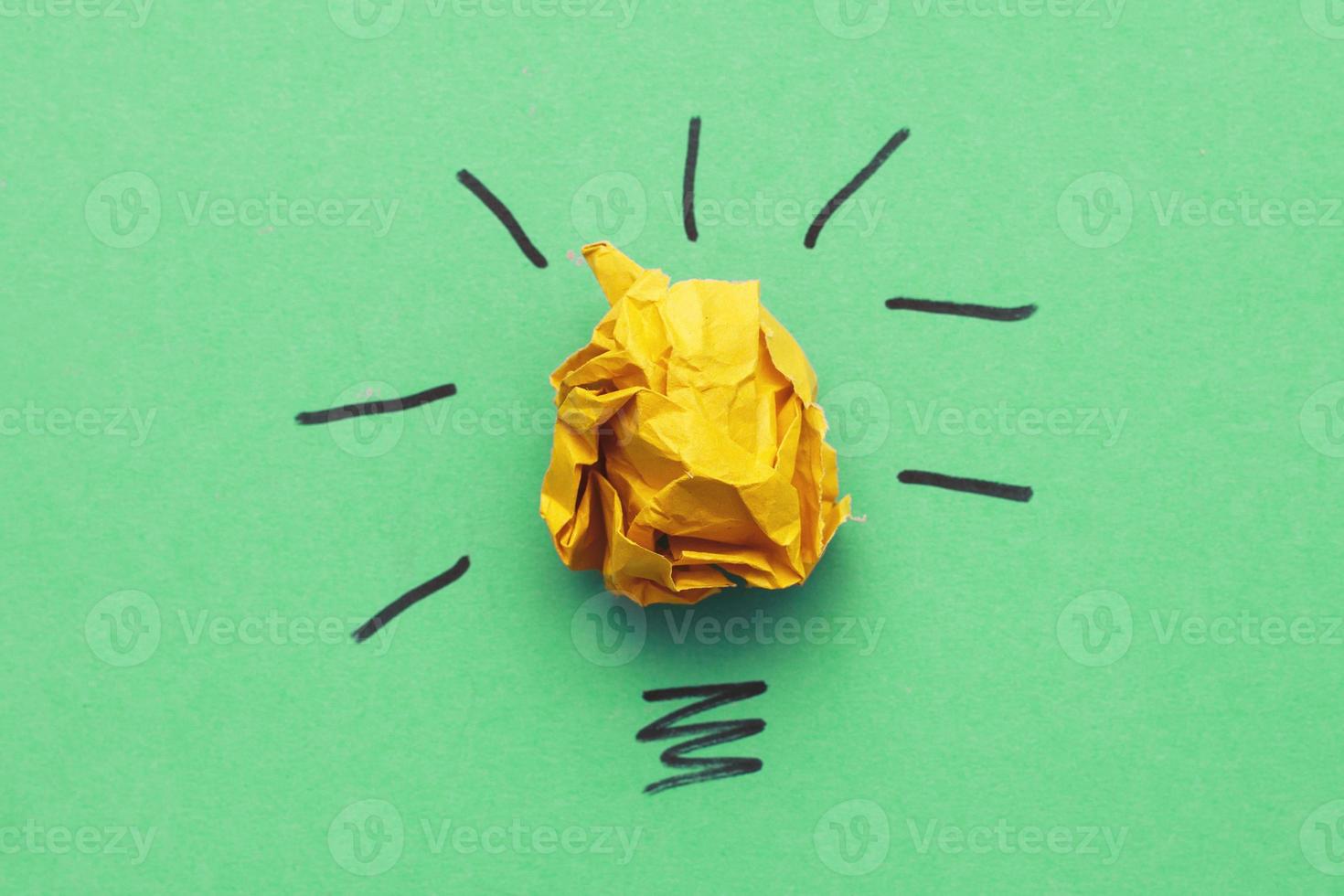 crumpled yelllow paper laightbulb as a concept creative idea and innovation on a green background photo