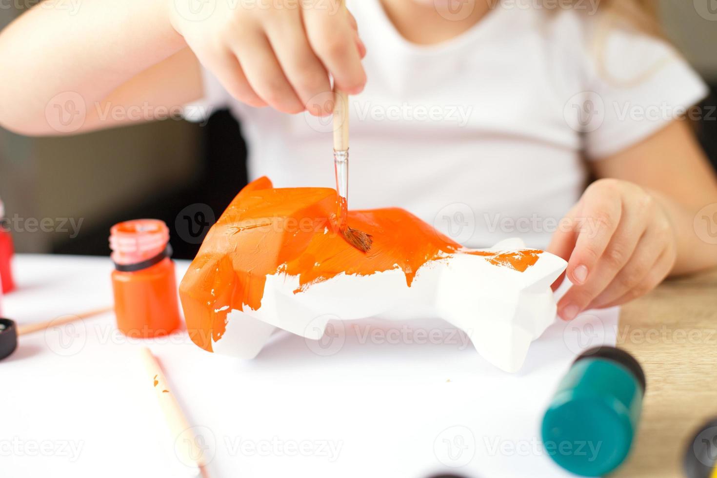 a little girl paints a toy fox made of clay. DIY concept photo