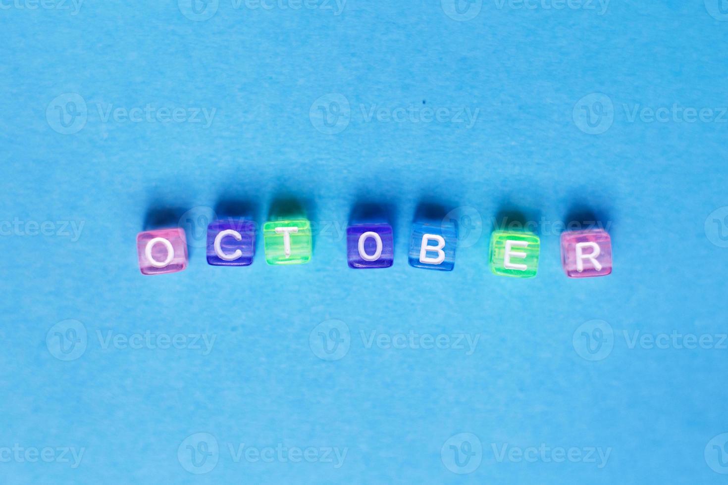 inscription october made by multicolor plastic cubes on a blue background. photo