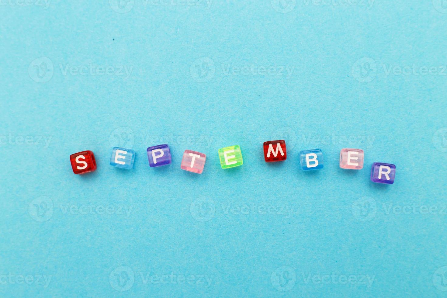 inscription September made by multicolor plastic cubes on a blue background. photo