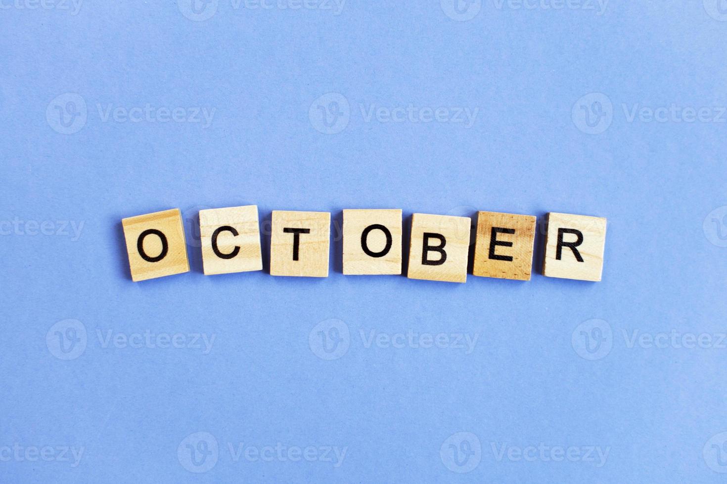 inscription October made by wooden cubes on a veri peri purple background. photo