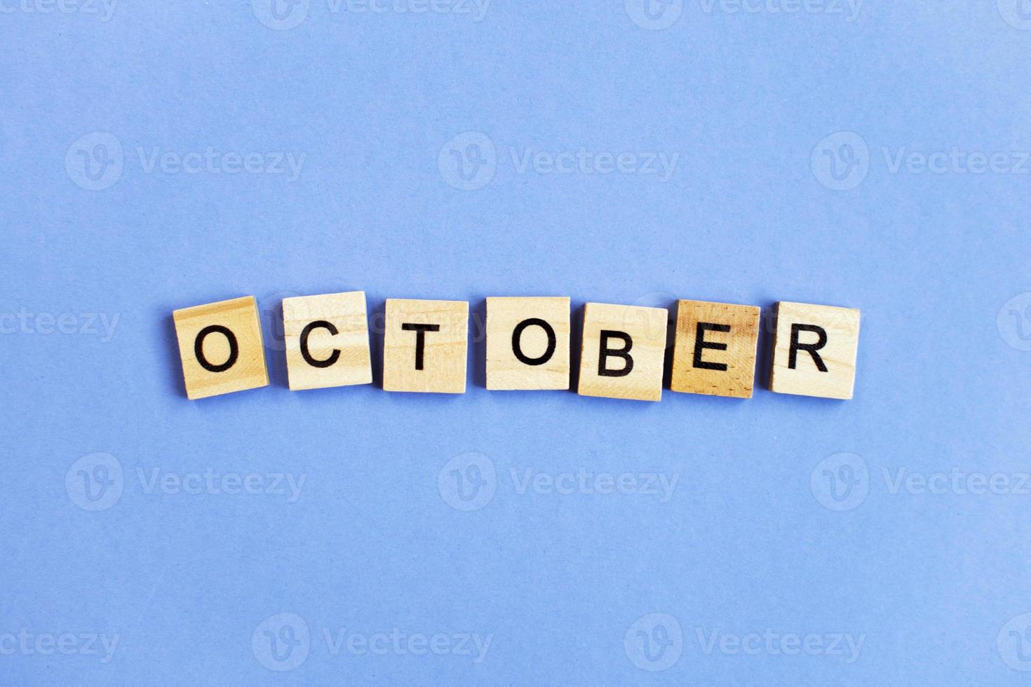 inscription October made by wooden cubes on a veri peri purple background. photo