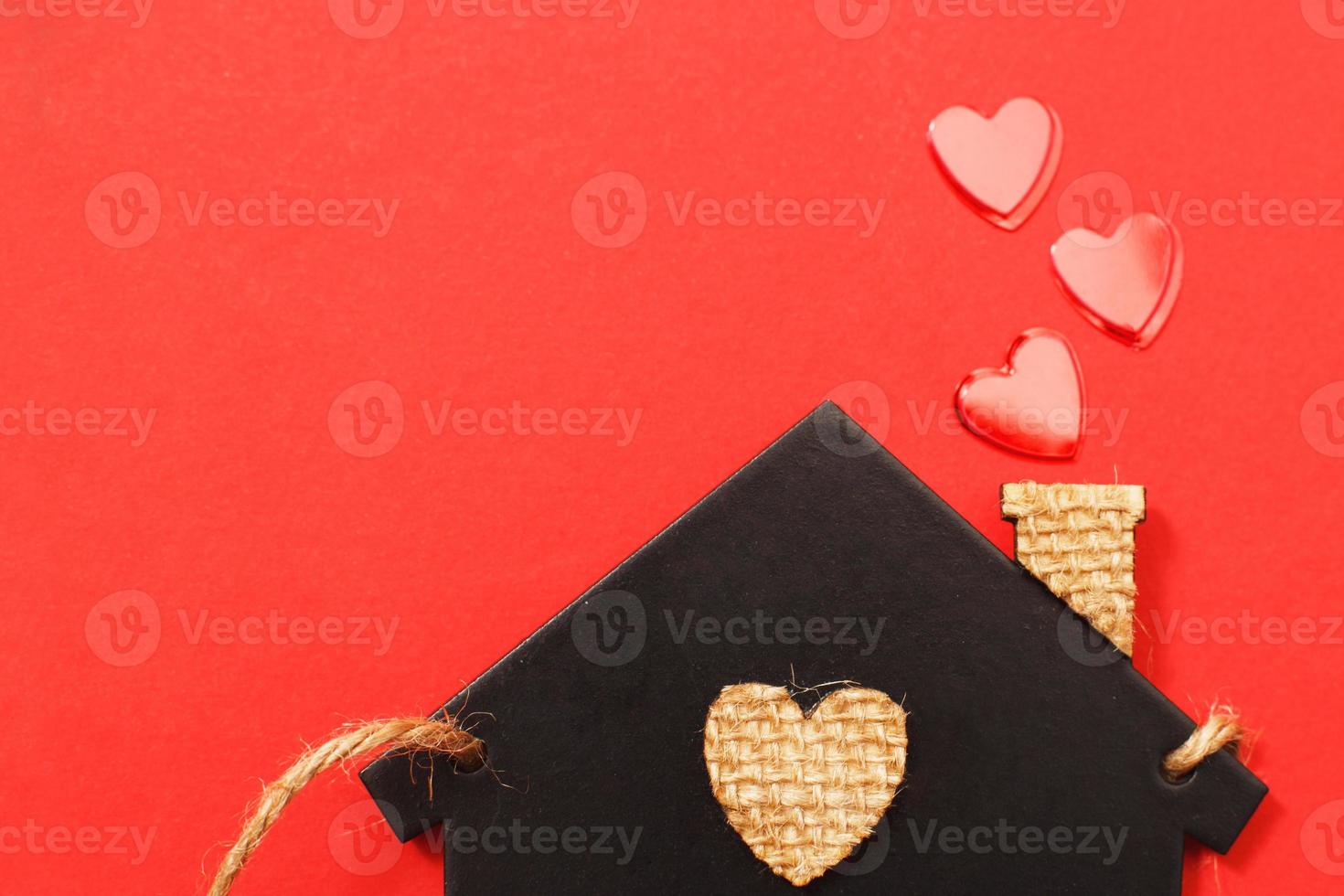 small toy house with red hearts from pipe on red background. Concept of love , family photo