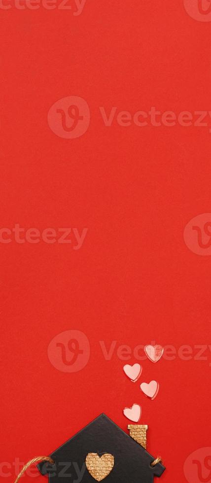 small toy house with red hearts from pipe on red background. Concept of love , family photo