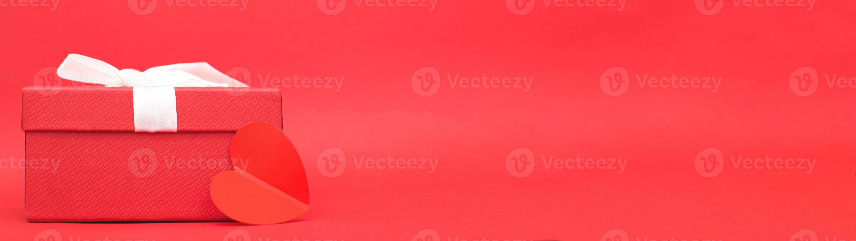Present box with a heart on a red background. photo