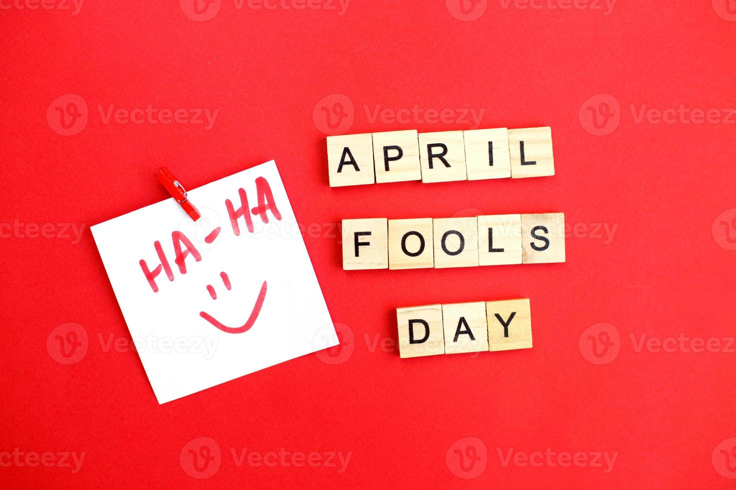 sticker with smiley and inscription april fools day made by wooden cubes on red background. photo