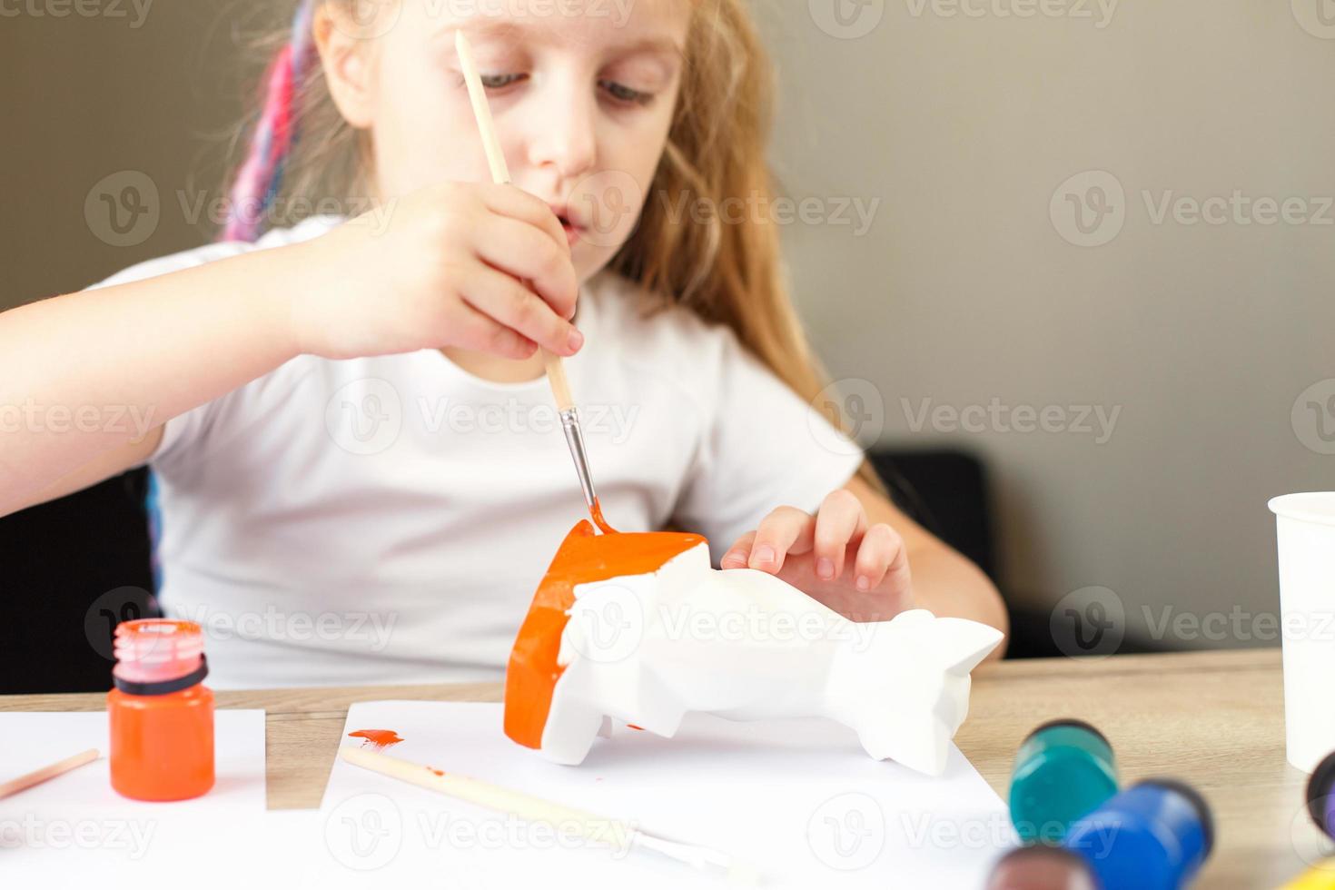 a little girl paints a toy fox made of clay. DIY concept photo